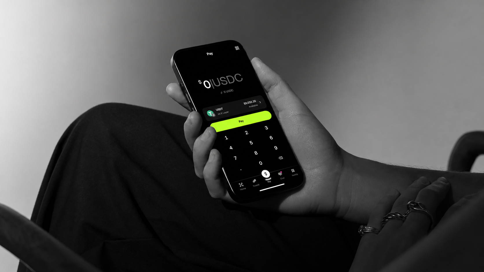 OKX Pay &mdash; someone mid-payment, holding their phone with the Pay screen and keypad open